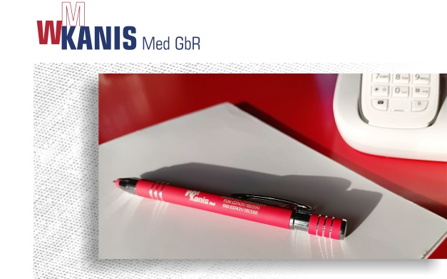 Rote Schreibtischplatte, auf der ein Schreibblock mit Stift liegt. Darüber das Firmenlogo.