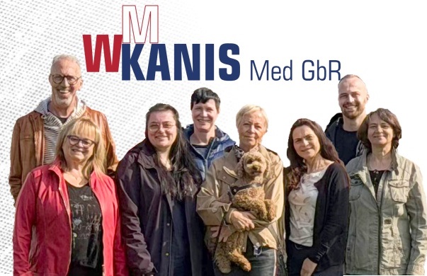 Gruppenfoto mit acht Personen, dahinter Firmenlogo aus roten Großbuchstaben W M und Kanis Med GbR in Blau.