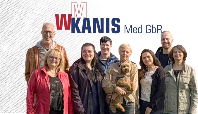Gruppenfoto mit neun Personen, dahinter Firmenlogo aus roten Großbuchstaben W M und Kanis Med GbR in Blau.